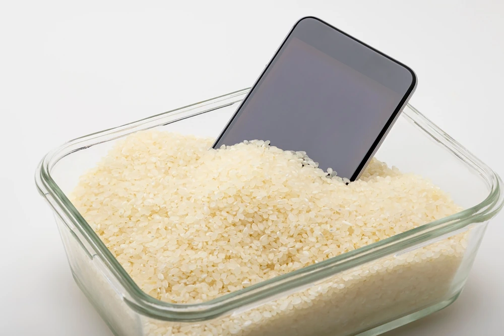 Ein nass gewordenes Smartphone liegt im Reis