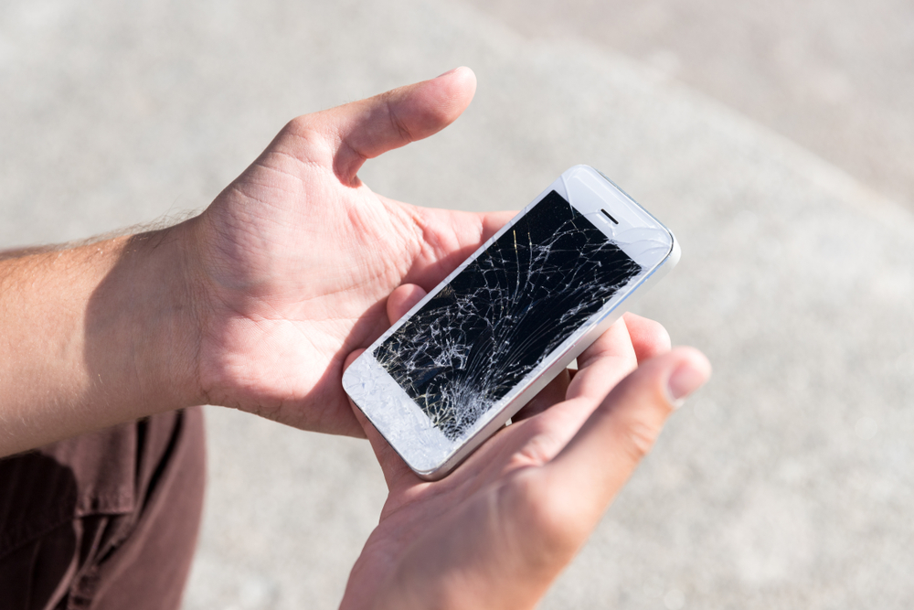 Displayriss: Mann hält defektes Smartphone in der Hand